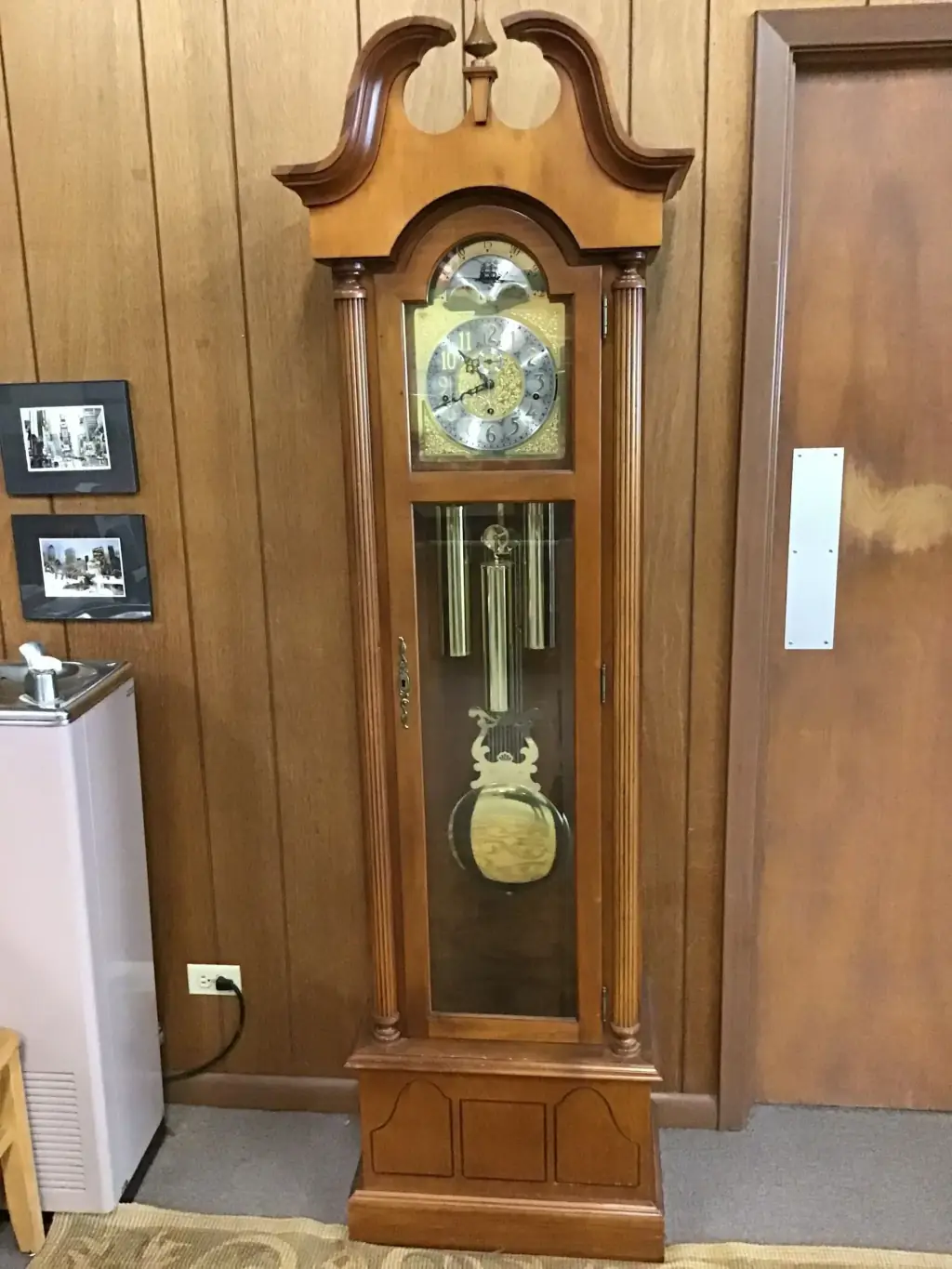 A grandfather clock in cherry finish standing on the showroom floor
