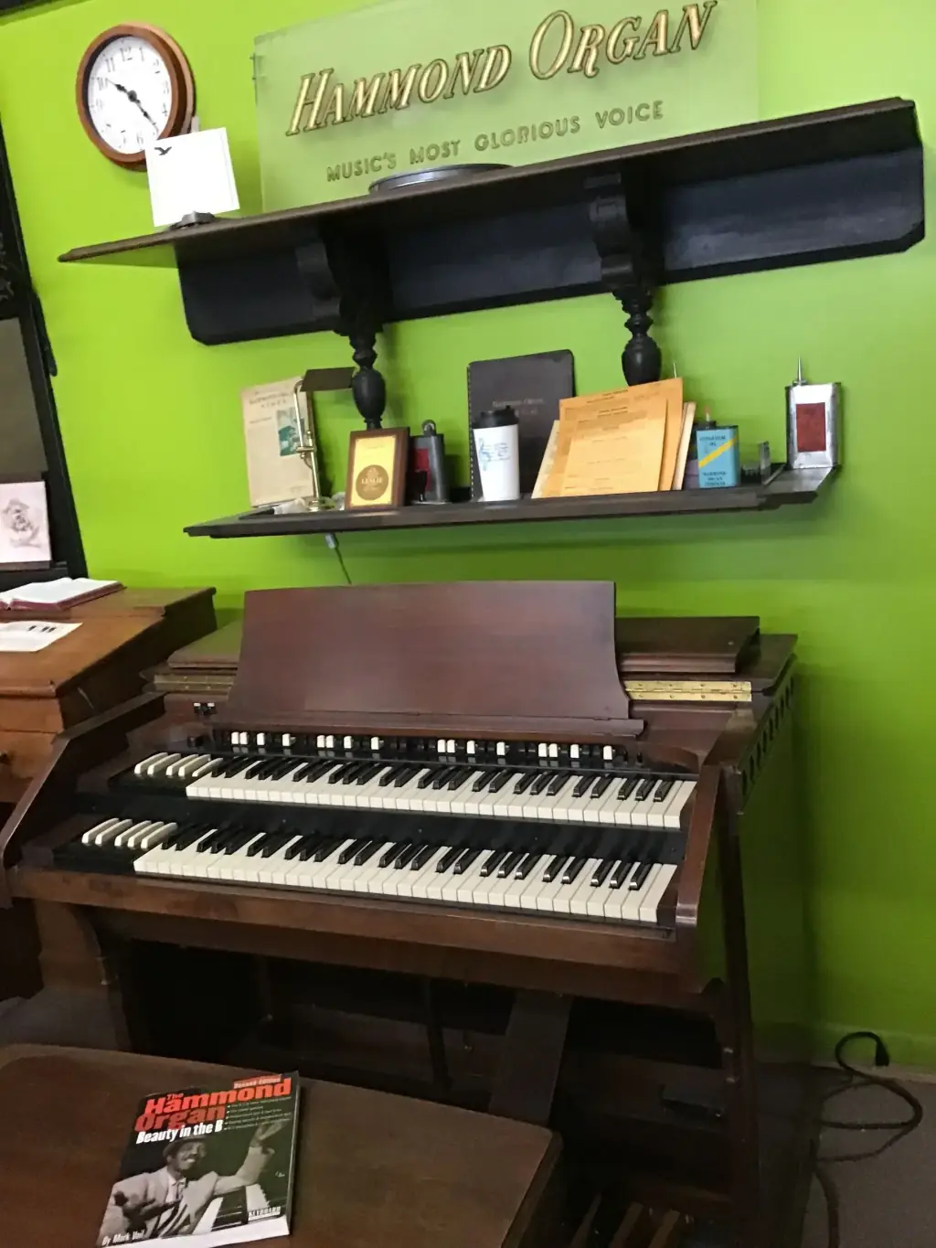 A Hammond console organ beneath the original Hammond Organ dealer sign reading Music's Most Glorious Voice