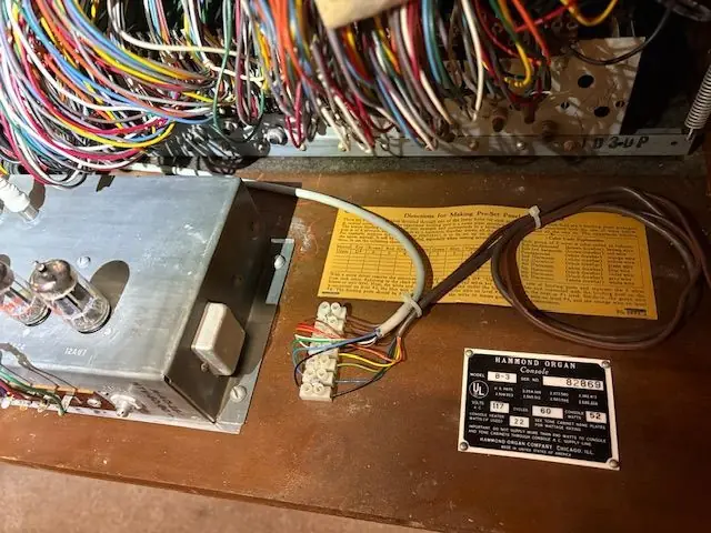An opened Hammond organ chassis showing its wiring loom and the riveted Hammond service plate