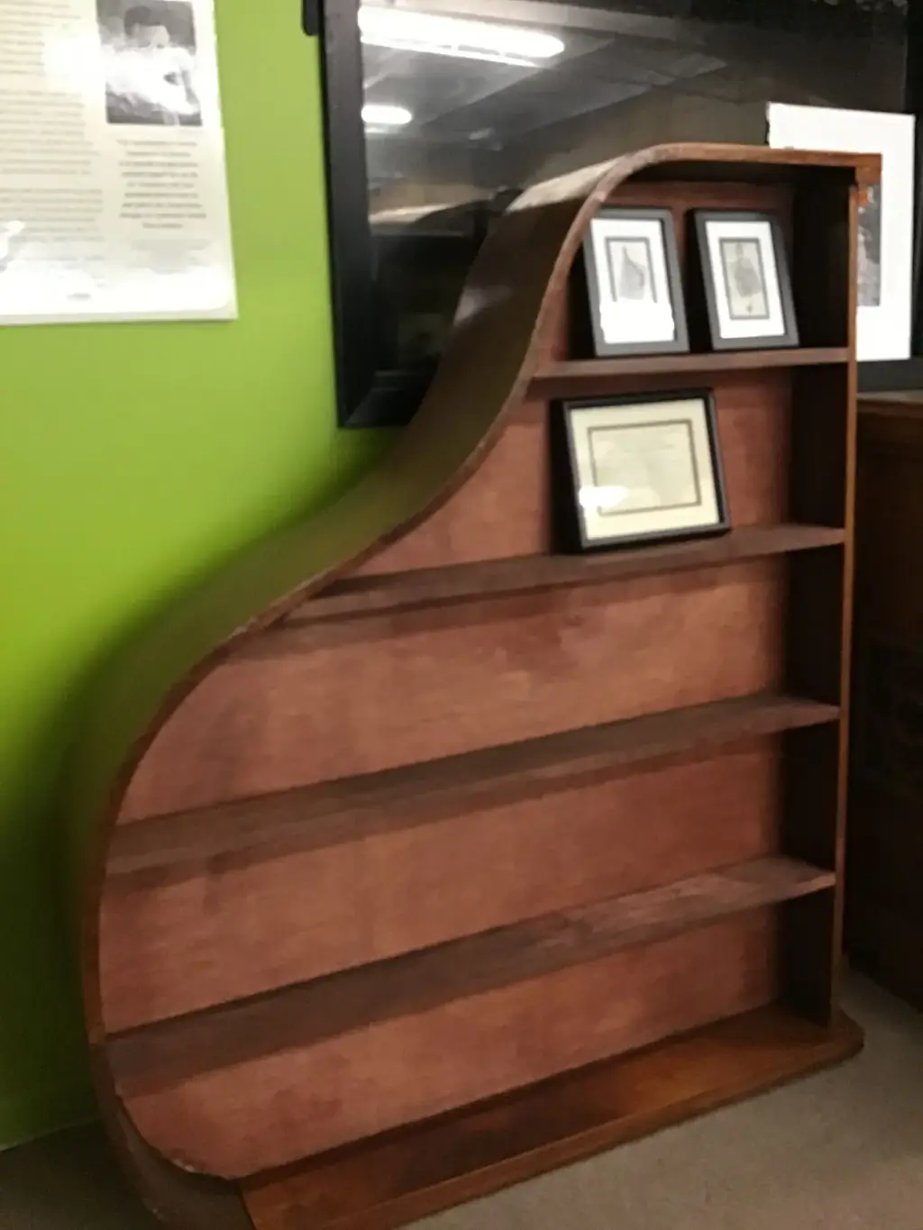 A retired grand piano case rebuilt into a curved bookshelf