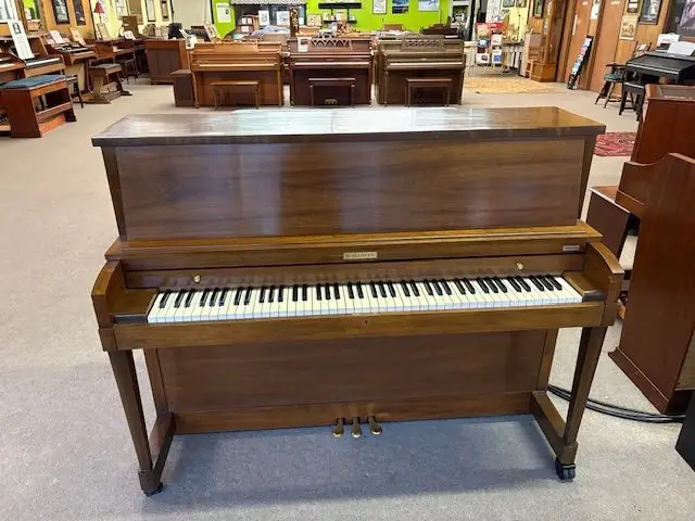 Rows of upright pianos receding down the Paul Hewitt Music showroom floor