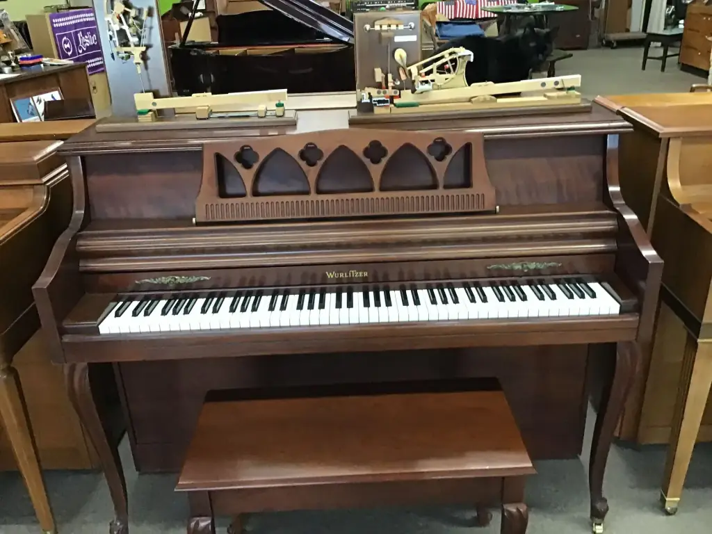 A Wurlitzer French Provincial console piano in cherry finish with carved fretwork